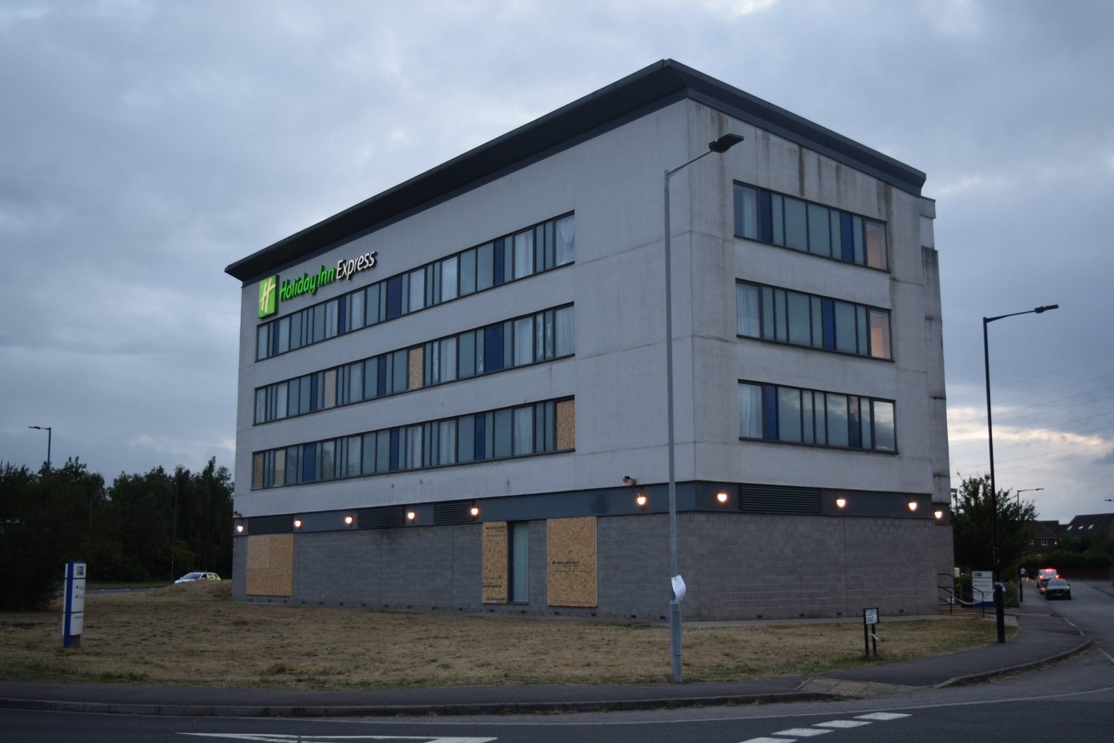 The Holiday Inn Rotherham North the evening after it was attacked: scorched brickwork, boarded windows and debris across the forecourt.
